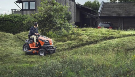 En man som klipper gräsmattan med en Husqvarna traktor