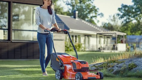 Kvinna som klipper gräsmattan med en Husqvarna batteridriven gräsklippare