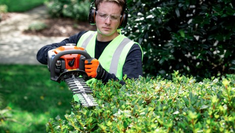 En man som klipper en häck med en Husqvarna bensindriven häcksax 522HDR60S